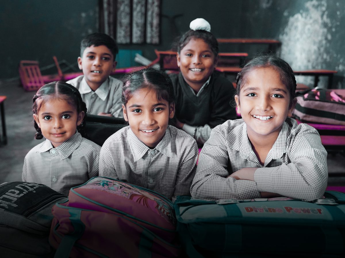 Students smiling at their desks in a government school classroom