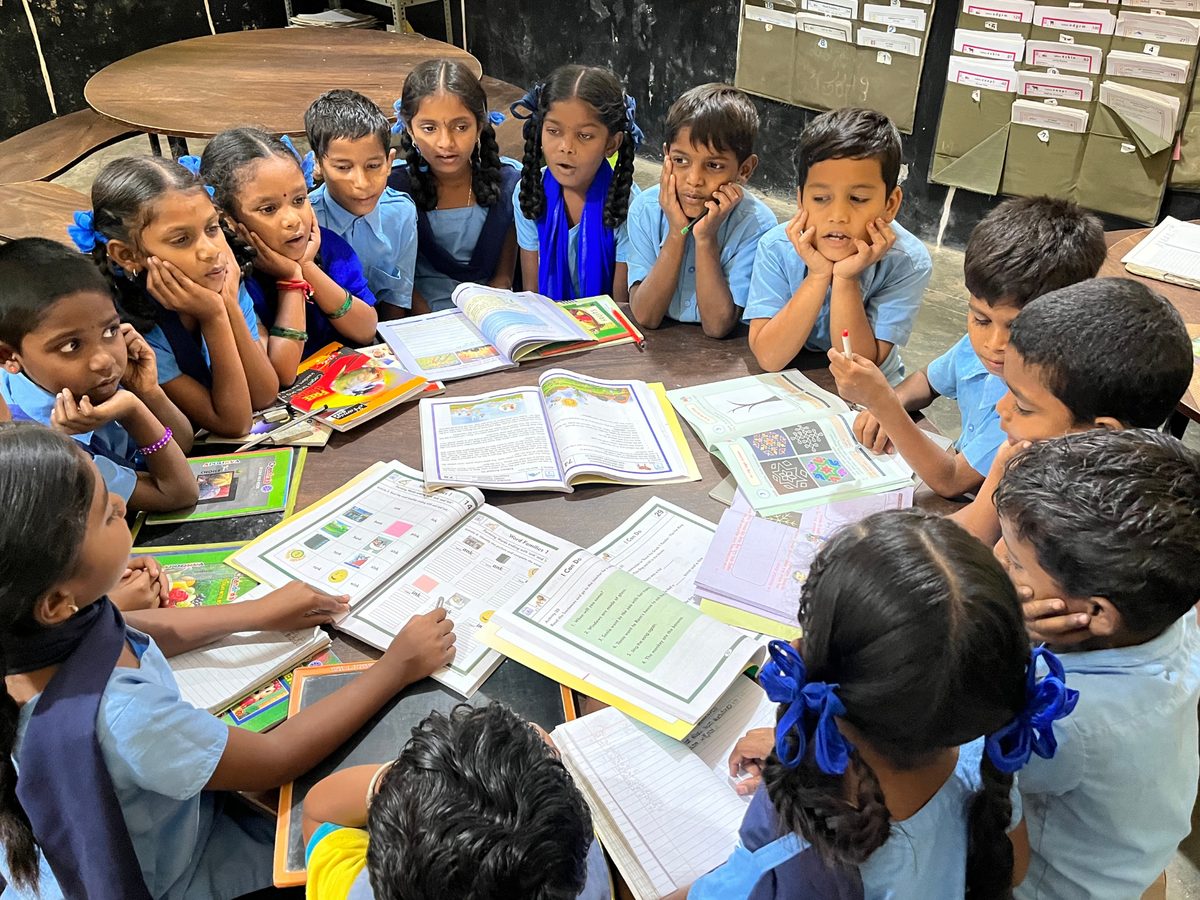 Children working together around a table of books in a peer learning circle