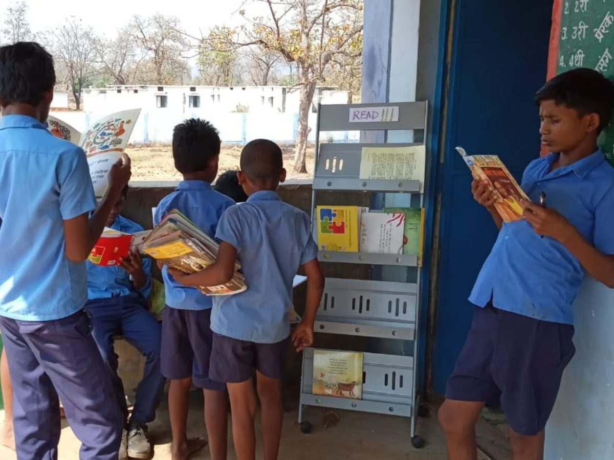 Boys choosing books from a reading rack outside their classroom