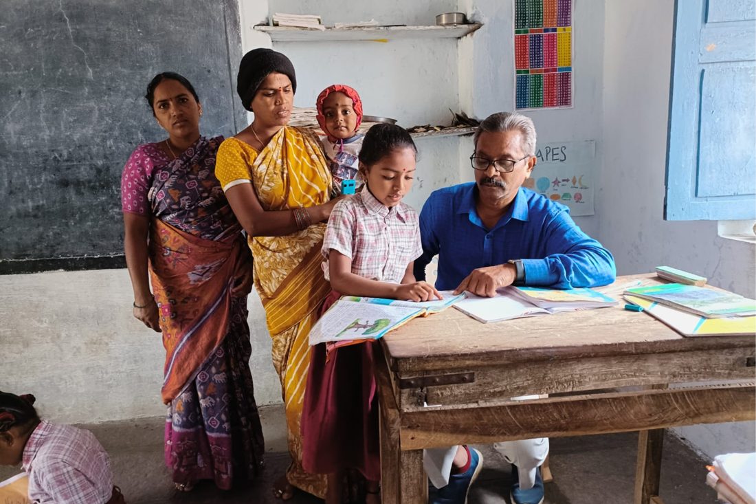 A teacher reviewing a student's work with her family at a parent-teacher meeting