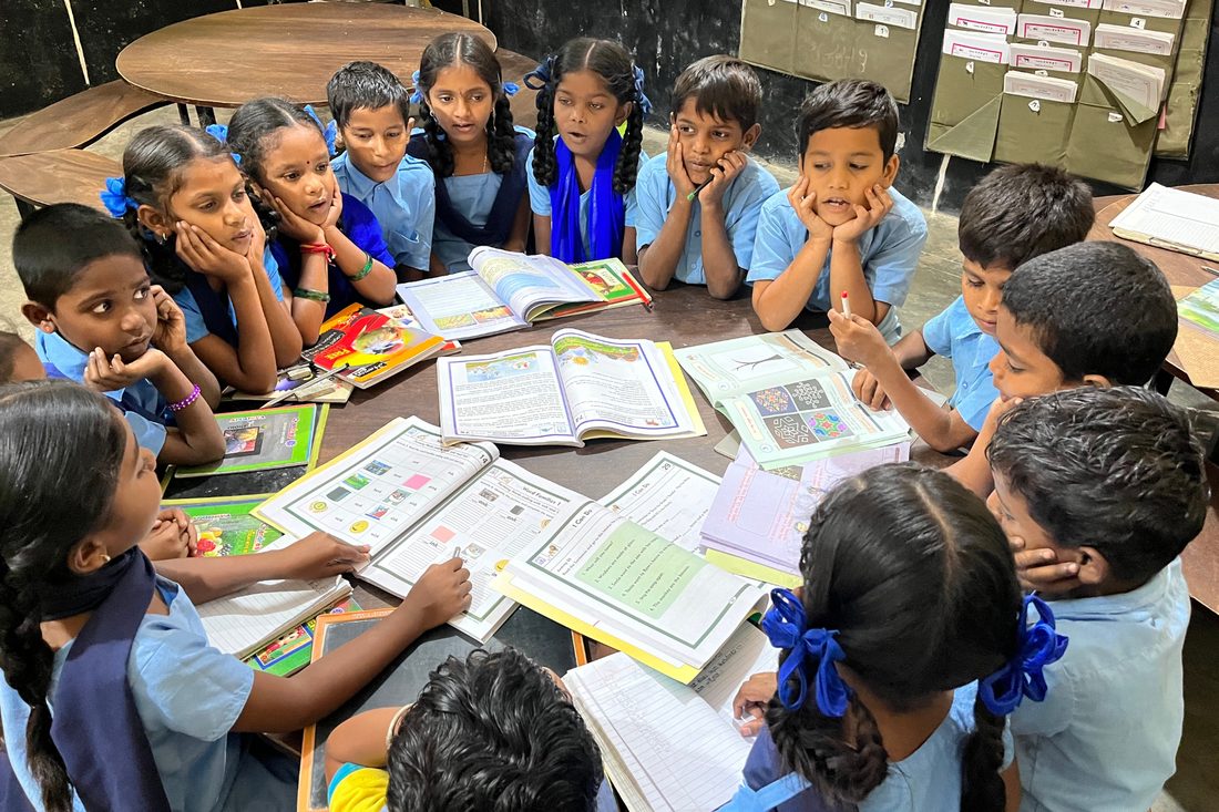 Children working together around a table of books in a peer learning circle