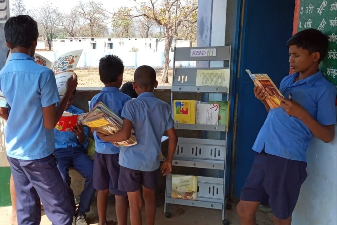 Boys choosing books from a reading rack outside their classroom