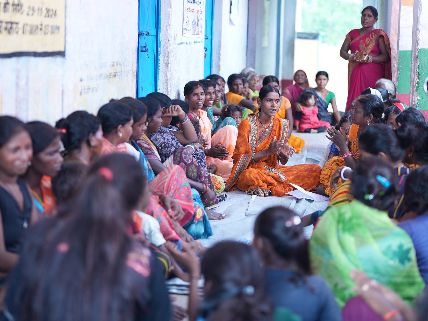 Women gathered together in a village courtyard for a community education meeting