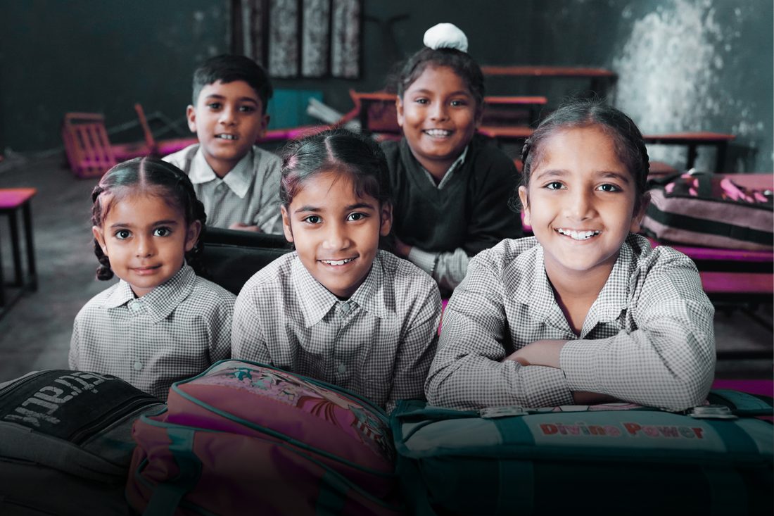 Students smiling at their desks in a government school classroom
